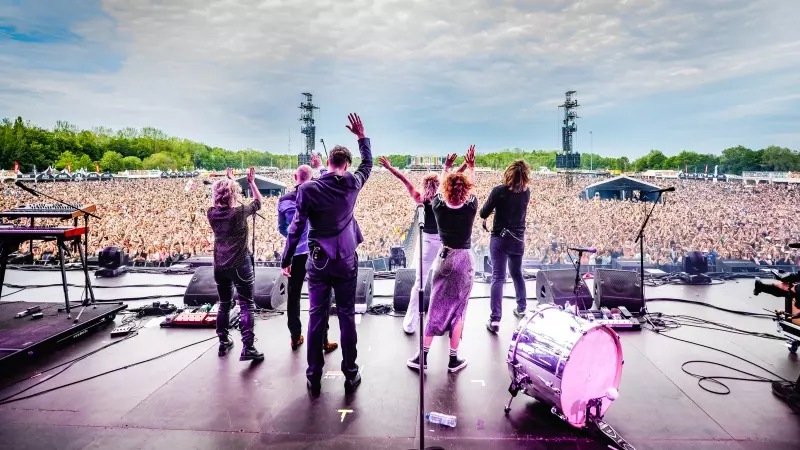 Band speelt voor groot publiek op festivalpodium.